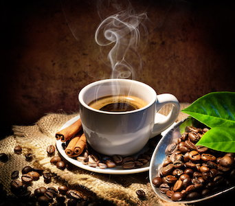 Steaming cup of coffee with coffee beans